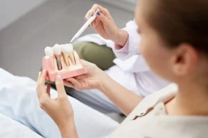 patient being shown the dental implant model